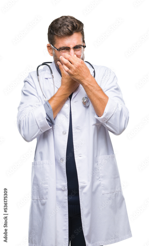 Young handsome doctor man over isolated background smelling something stinky and disgusting, intolerable smell, holding breath with fingers on nose. Bad smells concept.