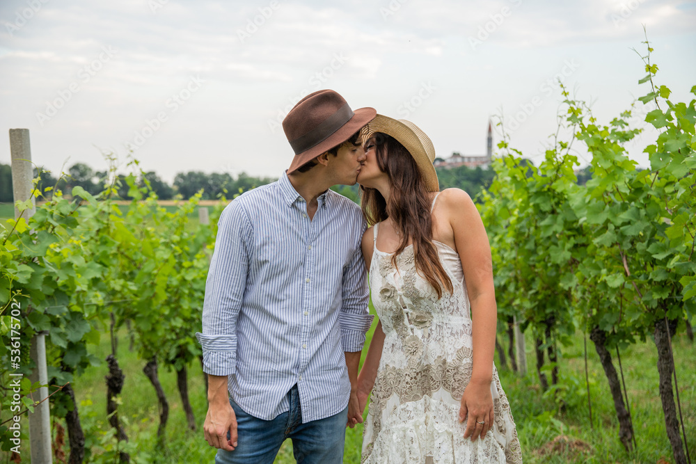 Young couple during a romantic walk in the vineyard stop and kiss each other on the mouth