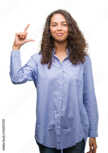 Young hispanic business woman smiling and confident gesturing with hand doing size sign with fingers while looking and the camera. Measure concept.