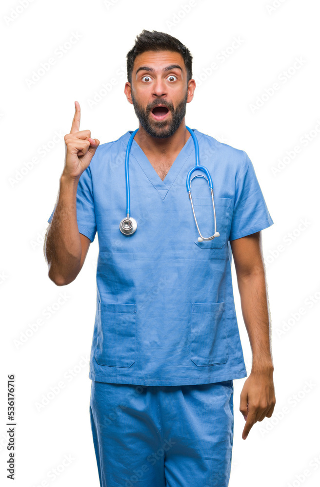 Adult hispanic doctor or surgeon man over isolated background pointing finger up with successful idea. Exited and happy. Number one.