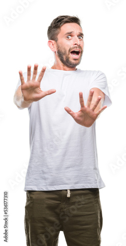 Fotografía Young handsome man over isolated background afraid and terrified with fear expression stop gesture with hands, shouting in shock