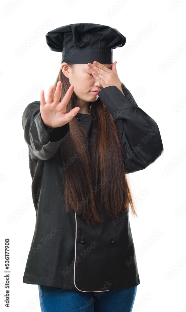 Young Chinese woman over isolated background wearing chef uniform covering eyes with hands and doing stop gesture with sad and fear expression. Embarrassed and negative concept. Young Chinese woman over isolated background wearing chef uniform covering eyes with hands and doing stop gesture with sad and fear expression. Embarrassed and negative concept.