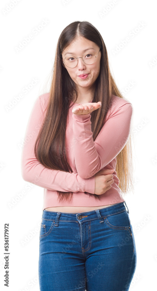 Obraz premium Young Chinese woman over isolated background wearing glasses looking at the camera blowing a kiss with hand on air being lovely and sexy. Love expression.