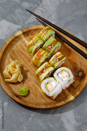 Sushi covered with avocado on wooden board gray stone background.