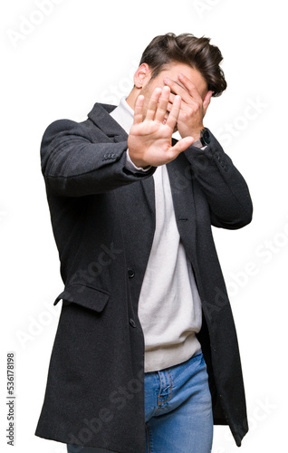 Young elegant man wearing winter coat over isolated background covering eyes with hands and doing stop gesture with sad and fear expression. Embarrassed and negative concept.