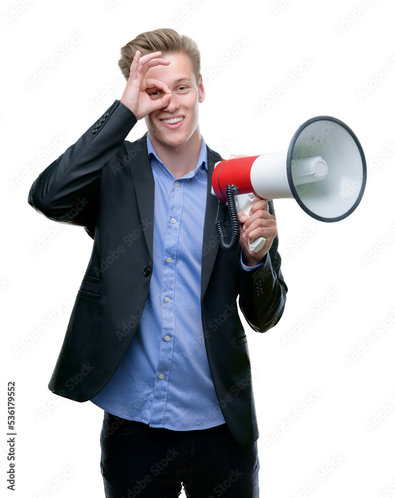 Young handsome blond man holding a megaphone with happy face smiling doing ok sign with hand on eye looking through fingers Young handsome blond man holding a megaphone with happy face smiling doing ok sign with hand on eye looking through fingers