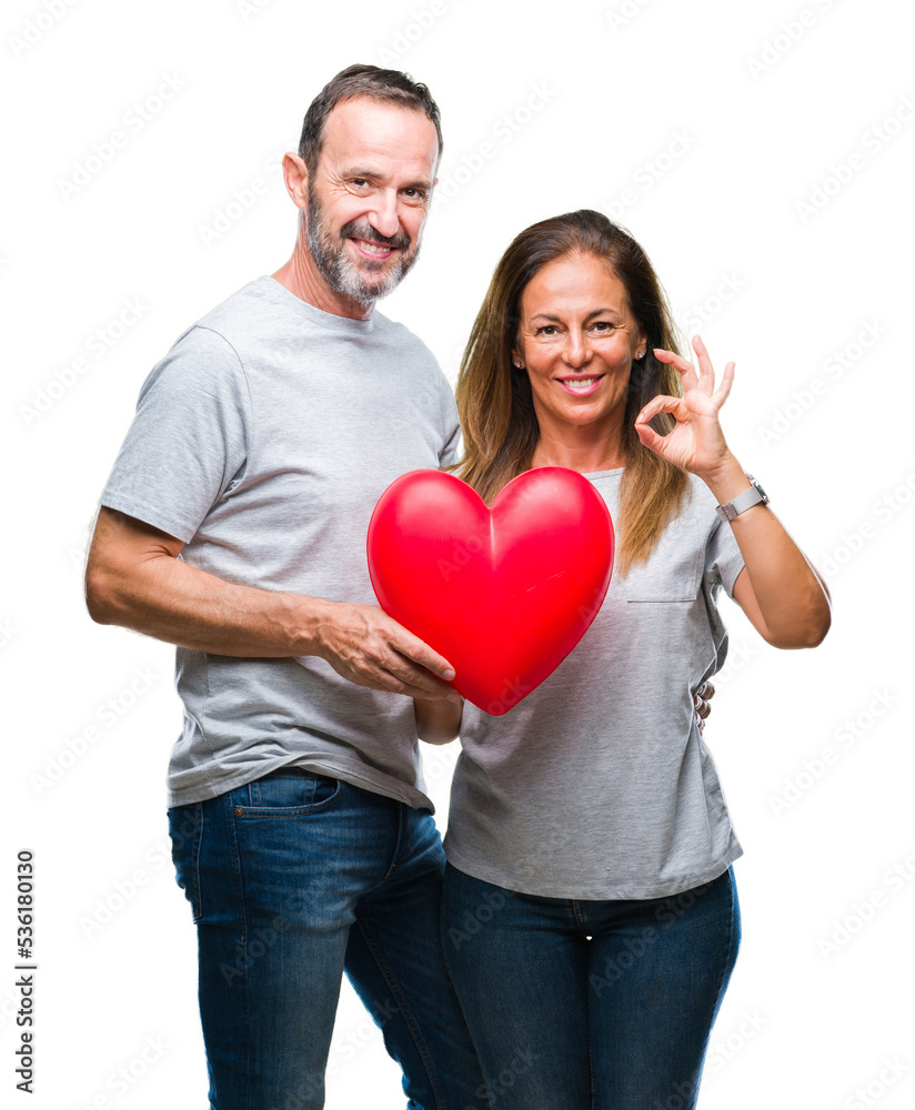 Middle age hispanic casual couple in love holding red heart over isolated background doing ok sign with fingers, excellent symbol Middle age hispanic casual couple in love holding red heart over isolated background doing ok sign with fingers, excellent symbol