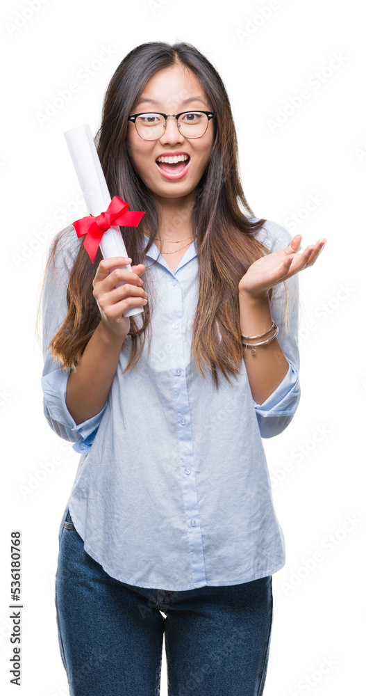 Young asian woman holding degree over isolated background very happy and excited, winner expression celebrating victory screaming with big smile and raised hands Young asian woman holding degree over isolated background very happy and excited, winner expression celebrating victory screaming with big smile and raised hands