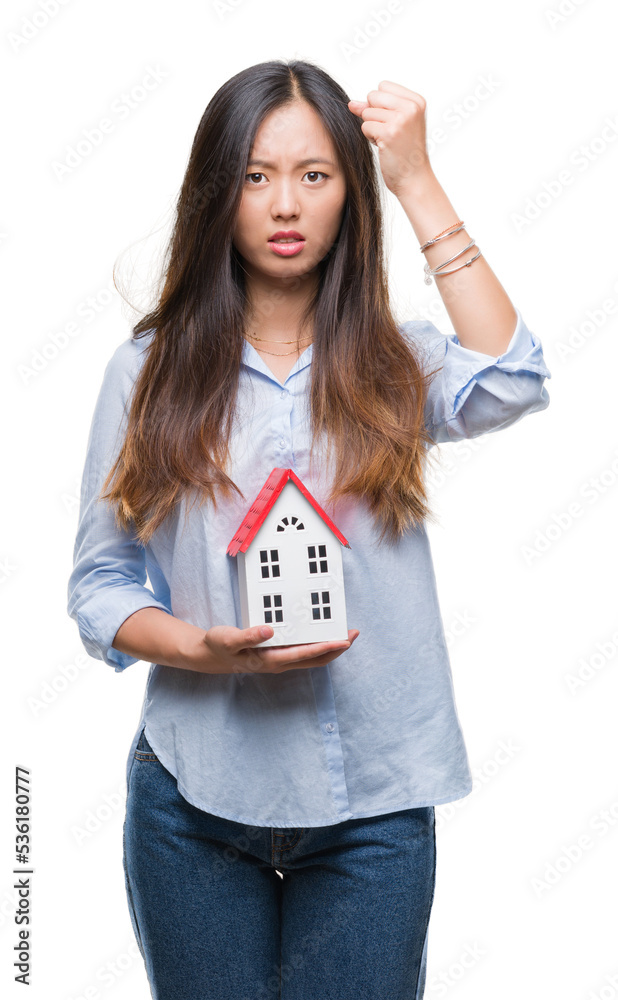 Young asian woman real state agent holding house isolated background annoyed and frustrated shouting with anger, crazy and yelling with raised hand, anger concept Young asian woman real state agent holding house isolated background annoyed and frustrated shouting with anger, crazy and yelling with raised hand, anger concept