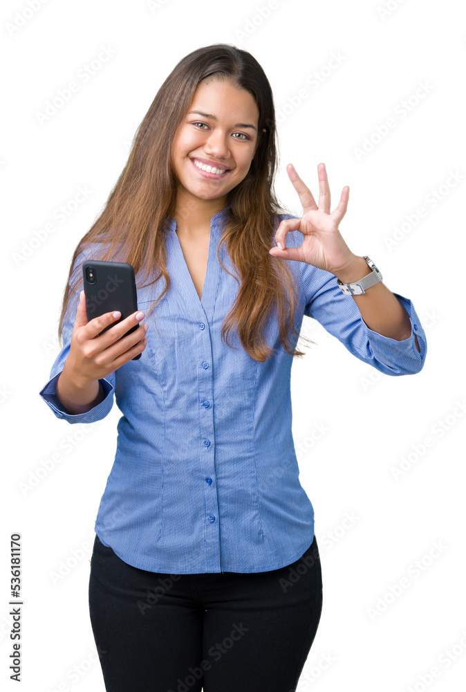 Young beautiful brunette business woman using smartphone over isolated background doing ok sign with fingers, excellent symbol Young beautiful brunette business woman using smartphone over isolated background doing ok sign with fingers, excellent symbol