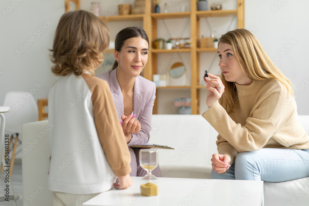 Mom with minor son reception with child psychologist. They play games. Psychologist takes notes and analyzes. Spacious office. Unrecognizable boy. Blurred foreground.