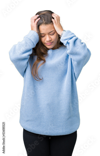Young beautiful brunette woman wearing blue winter sweater over isolated background suffering from headache desperate and stressed because pain and migraine. Hands on head. © Krakenimages.com