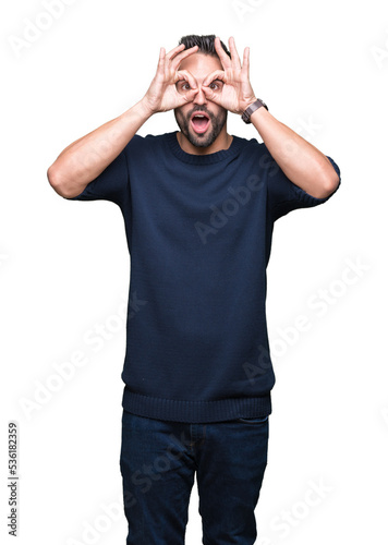 Young handsome man wearing sweater over isolated background doing ok gesture like binoculars sticking tongue out, eyes looking through fingers. Crazy expression.