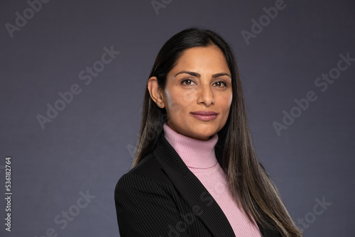 Studio headshots of beautiful Asian Indian woman in business attire on gray background. 