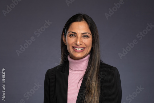 Studio headshots of beautiful Asian Indian woman in business attire on gray background. 