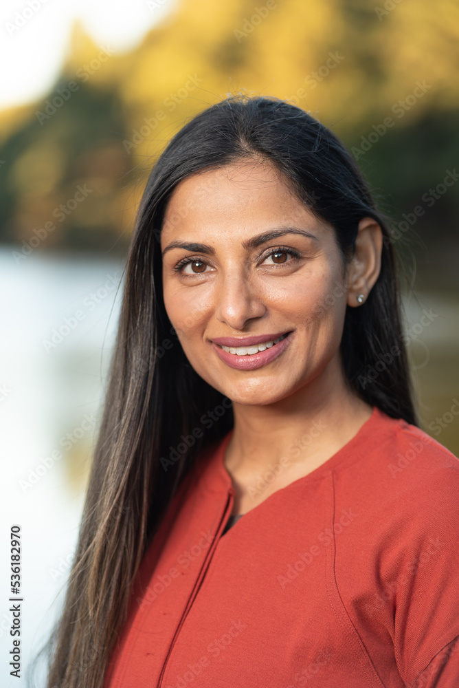 Beautiful Asian Indian woman wearing jeans and a red sweater by a lake. Beautiful Asian Indian woman wearing jeans and a red sweater by a lake.