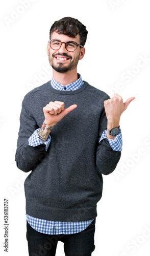 Young handsome smart man wearing glasses over isolated background Pointing to the back behind with hand and thumbs up, smiling confident photo