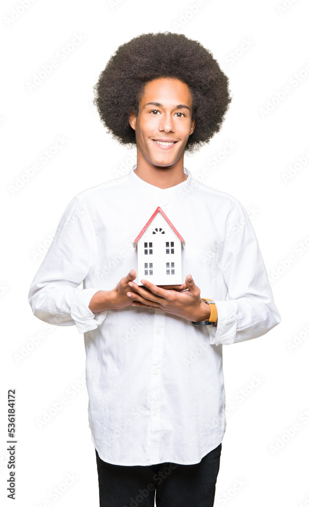 Young african american man with afro hair holding house with a happy face standing and smiling with a confident smile showing teeth Young african american man with afro hair holding house with a happy face standing and smiling with a confident smile showing teeth