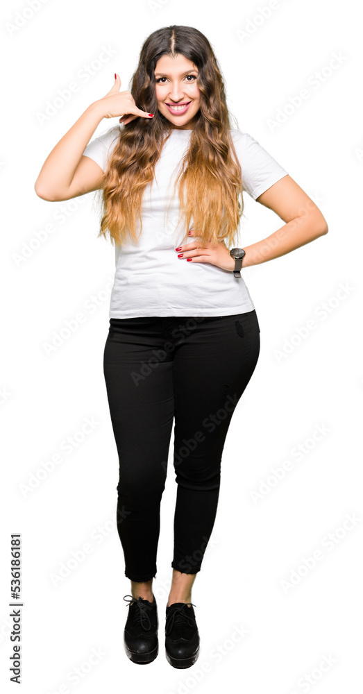 Young beautiful woman wearing casual white t-shirt smiling doing phone gesture with hand and fingers like talking on the telephone. Communicating concepts. Young beautiful woman wearing casual white t-shirt smiling doing phone gesture with hand and fingers like talking on the telephone. Communicating concepts.