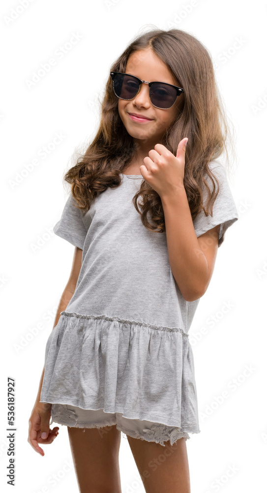 Brunette hispanic girl wearing sunglasses doing happy thumbs up gesture with hand. Approving expression looking at the camera with showing success. Brunette hispanic girl wearing sunglasses doing happy thumbs up gesture with hand. Approving expression looking at the camera with showing success.