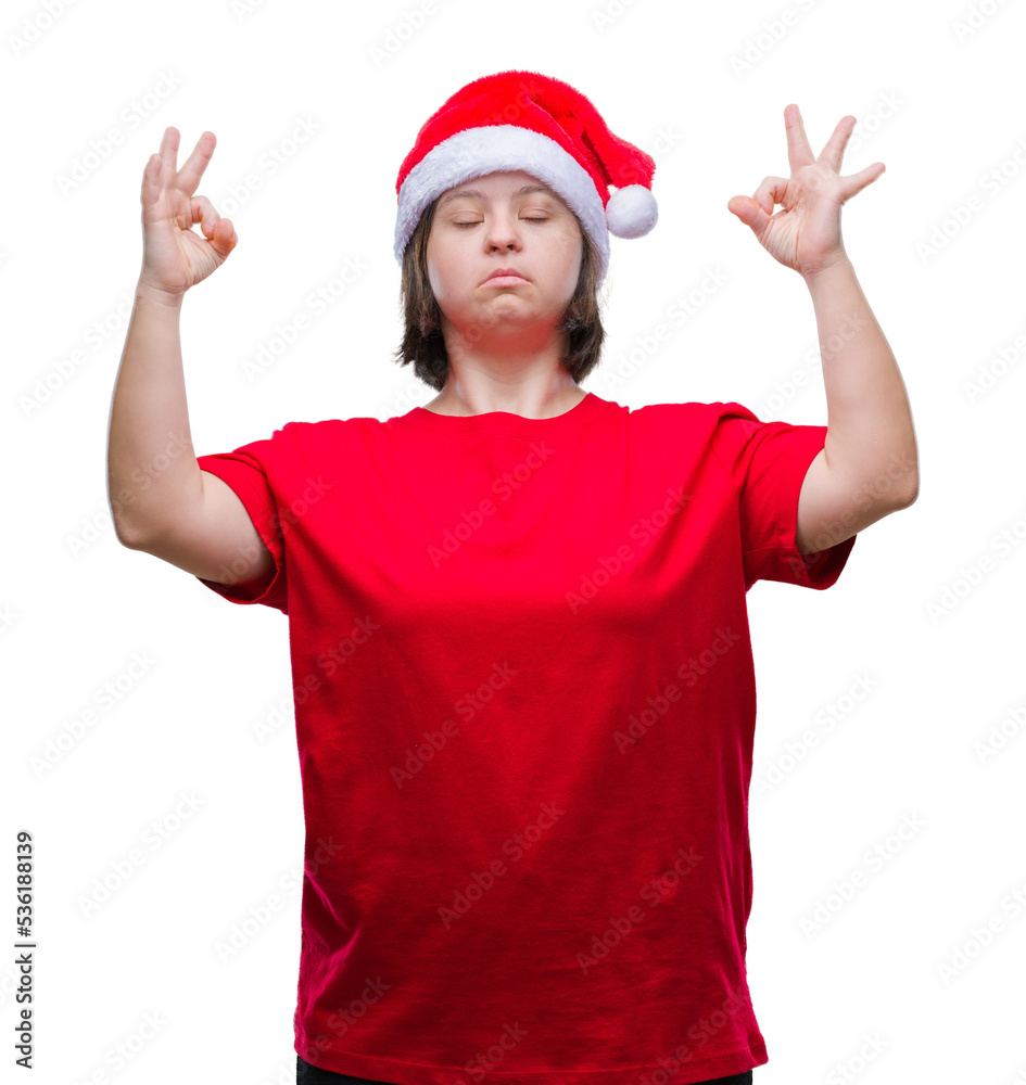 Young adult woman with down syndrome wearing christmas hat over isolated background relax and smiling with eyes closed doing meditation gesture with fingers. Yoga concept. Young adult woman with down syndrome wearing christmas hat over isolated background relax and smiling with eyes closed doing meditation gesture with fingers. Yoga concept.