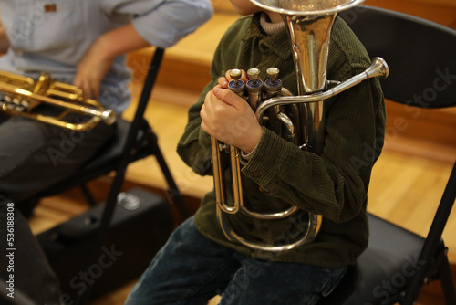 Child boy musician sitting in a classroom with a musical instrument tuba at a school music lesson in a jazz band.Background image close-up concept of education leisure and development of children