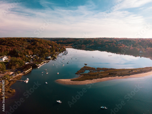 Cold Spring Harbor, New York with sandbar, woods, and various boats in the water.