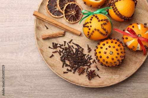 Pomander balls made of tangerines with cloves on wooden table, top view