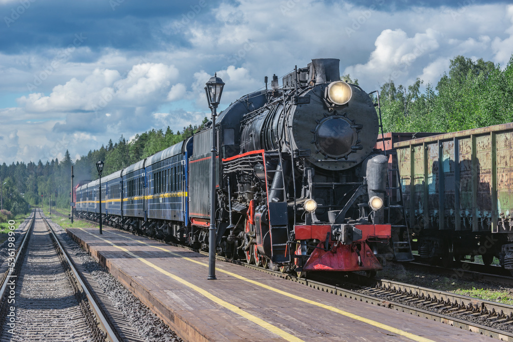 Naklejka premium Retro steam train approaches to the platform.