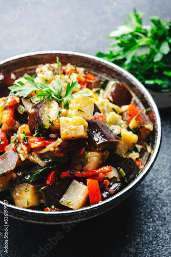 Vegetable stew, saute or caponata. Stewed eggplant with paprika, tomatoes, herbs and spices. Black kitchen table background, top view, copy space