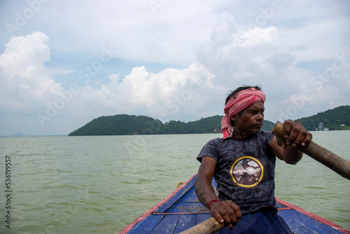 a poor tribal man pulling boat by his hand with paddle photo