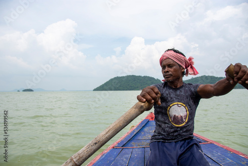 a poor tribal man pulling boat by his hand with paddle photo