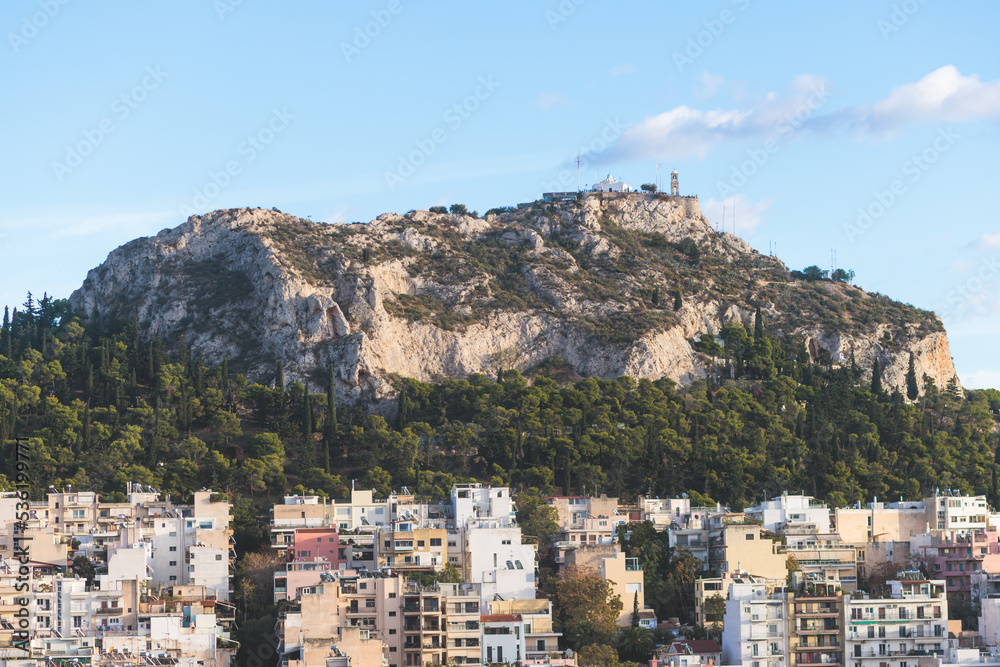 Fototapeta premium Athens, Attica, beautiful super-wide angle view of Athens, Greece, with Acropolis, Mount Lycabettus, mountains and scenery beyond the city, seen from Strefi Hill park in Exarcheia neighbourhood