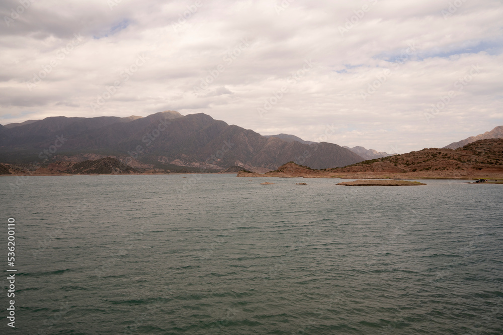 View of the reservoir in Potrerillos, Mendoza. The arid environment, turquoise glacier water lake and Andes mountains in the background.