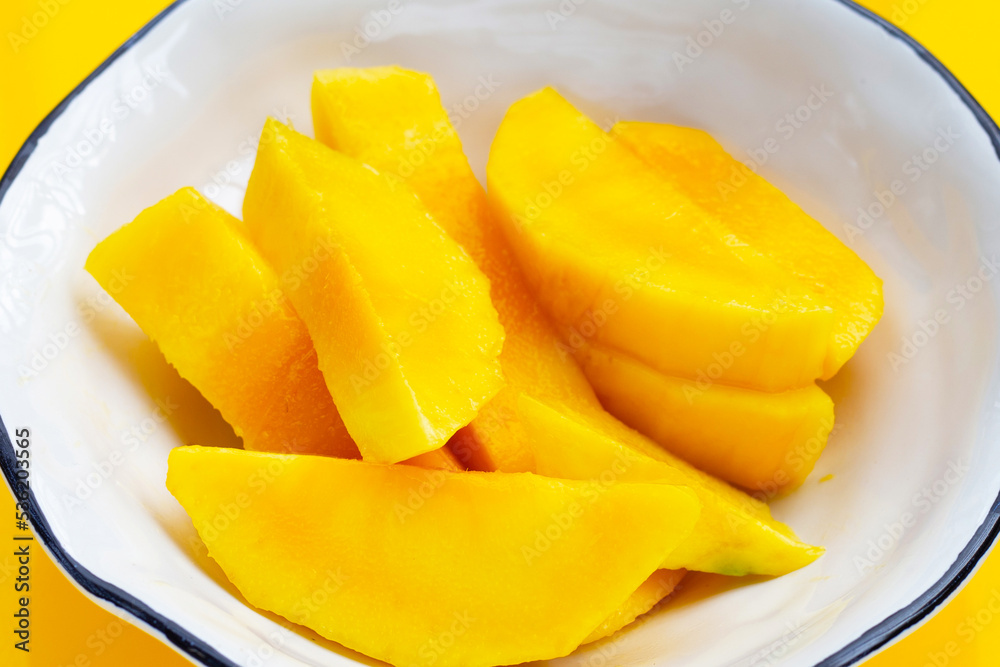 Yellow mango slices in bowl on yellow background. Yellow mango slices in bowl on yellow background.