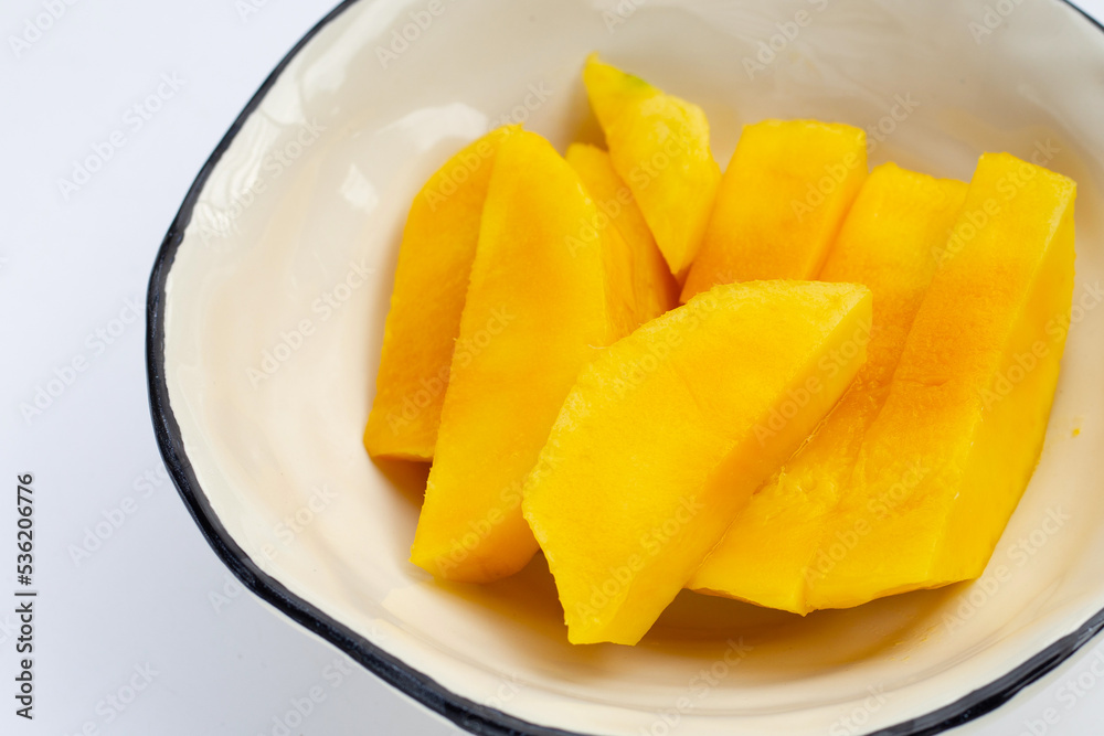 Yellow mango slices on white bowl Yellow mango slices on white bowl