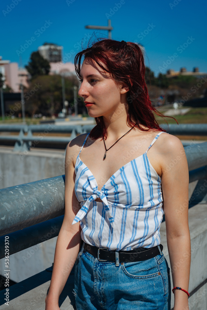 Beautiful young Hispanic redhead looking to her right. Medium shot, portrait orientation.