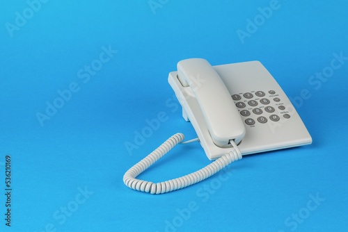 A white telephone with gray buttons on a blue background. photo