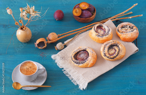 Mini pies filled with ground poppy seeds with fresh plums on blue wooden table, High angle of view, no people.
