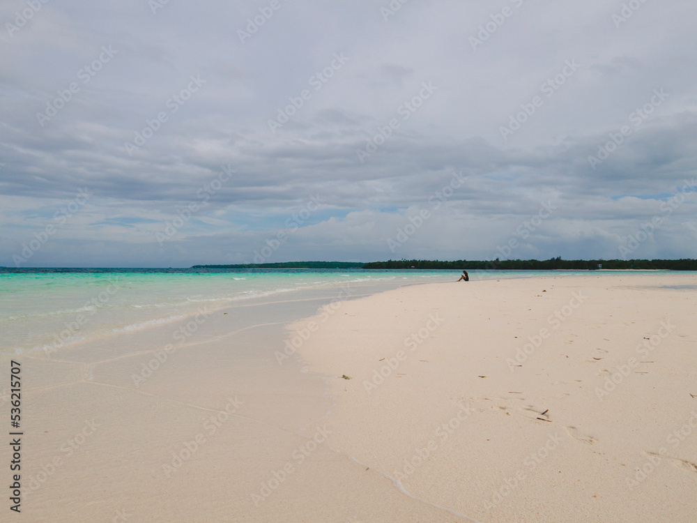 Beautiful sunny day on a calm pristine beach with grey skies in Indonesia