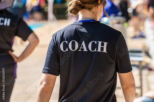 Back view of swimming coaches, wearing COACH shirt