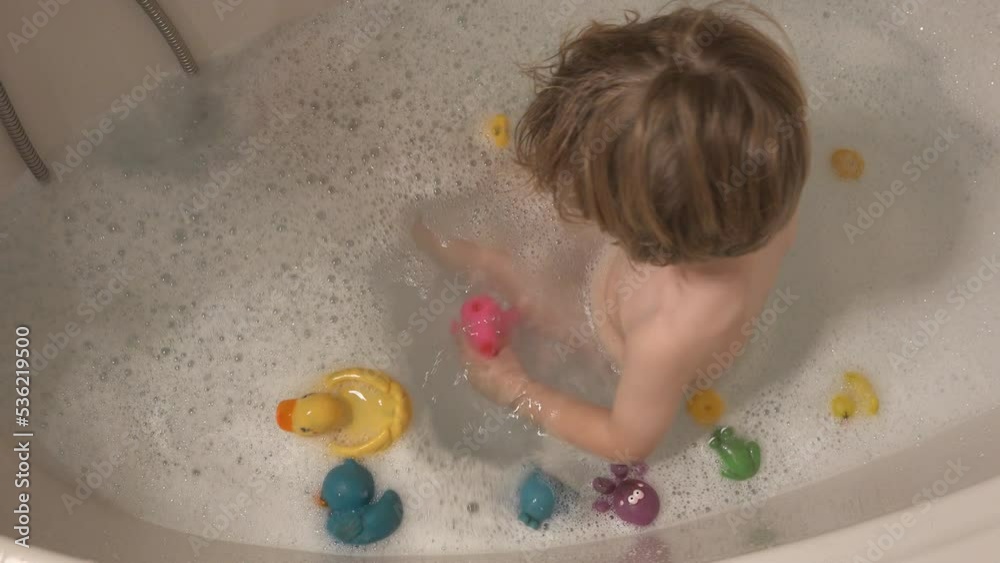 Little boy playing with rubber colorful ducklings in the bathtub Little boy playing with rubber colorful ducklings in the bathtub