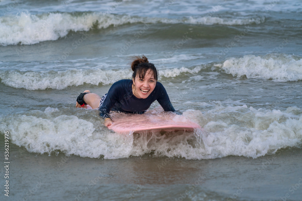 Asian tourists are happy, water sports activities, lie on the serving board, try to practice surfing on the shores of the sea. Adventure and surfing concept Asian tourists are happy, water sports activities, lie on the serving board, try to practice surfing on the shores of the sea. Adventure and surfing concept