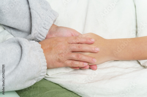 Mom holds the hand of a sick teenager girl, strokes her hand, encourages.