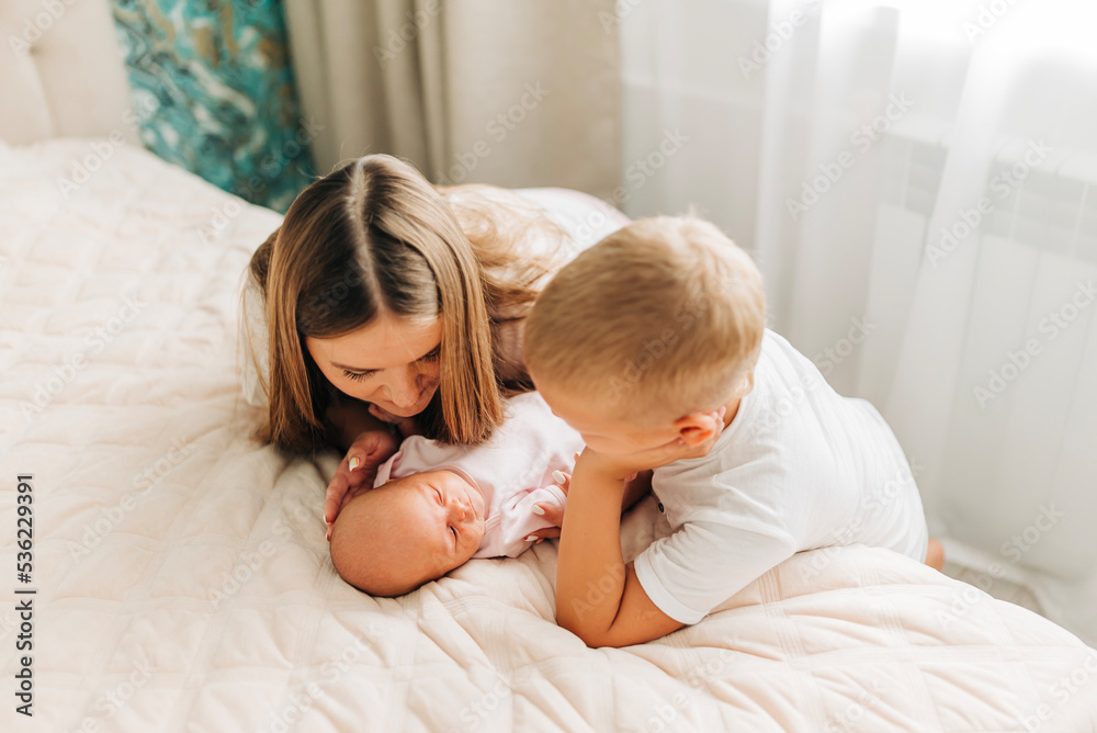 Lifestyle family portrait of parents with newborn baby child and older son. Happiness and love at home indoors Lifestyle family portrait of parents with newborn baby child and older son. Happiness and love at home indoors