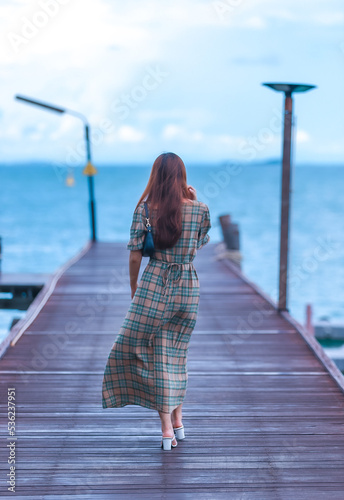 Asian pretty gilr wearing dress so alone feeling with walking and sit on walk way to to sea on evening