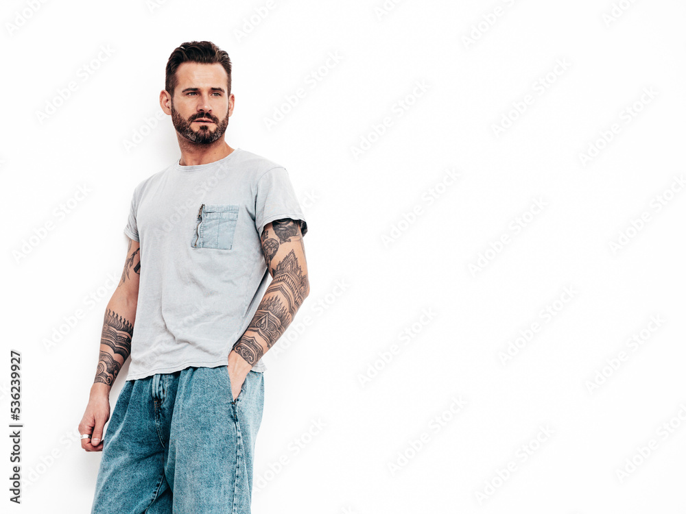 Portrait of handsome confident stylish hipster lambersexual model. Sexy man dressed in T-shirt and jeans. Fashion male isolated on white wall in studio Portrait of handsome confident stylish hipster lambersexual model. Sexy man dressed in T-shirt and jeans. Fashion male isolated on white wall in studio