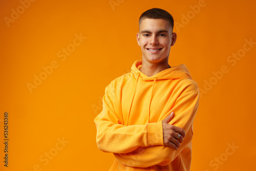 Happy smiling young man looking to camera over yellow background