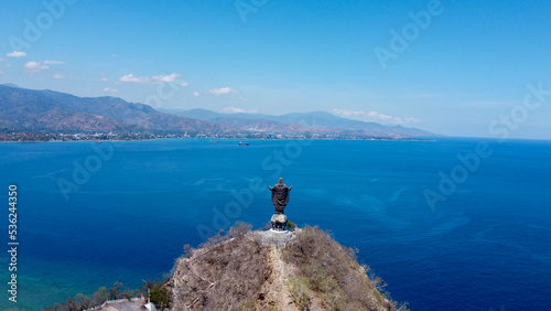 Popular landmark of Cristo Rei statue overlooking blue ocean and capital city of Dili, Timor Leste, South East Asia, aerial drone view of landscape and ocean photo