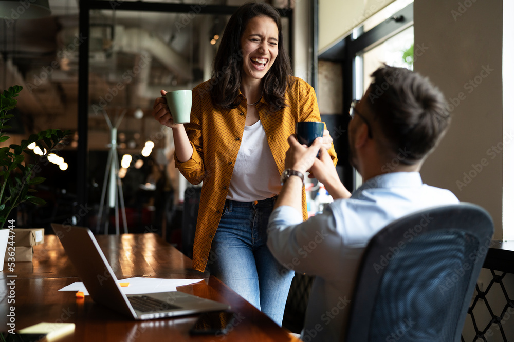 Colleagues laughing in office. Businesswoman and businessman drinking coffee Colleagues laughing in office. Businesswoman and businessman drinking coffee
